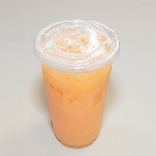 A plastic cup of iced Thai tea with a clear lid, filled with ice and a creamy orange beverage.