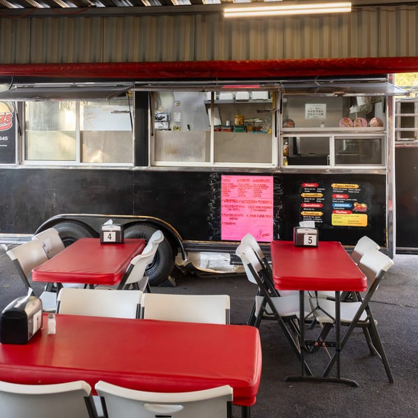 Lupita's food truck with red tables and white chairs set up for outdoor dining.