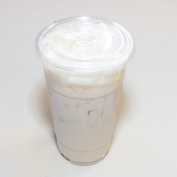A clear plastic cup filled with a light-colored iced beverage and a clear lid.