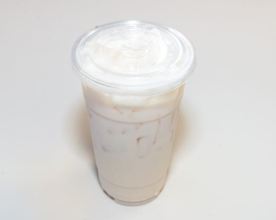 A clear plastic cup filled with a light-colored iced beverage and a clear lid.